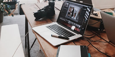 a laptop,camera,files and pen on desk